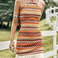 Colorful Aztec print halter neck mini dress with fringe hem detail on a woman standing near a white fence in a green field.