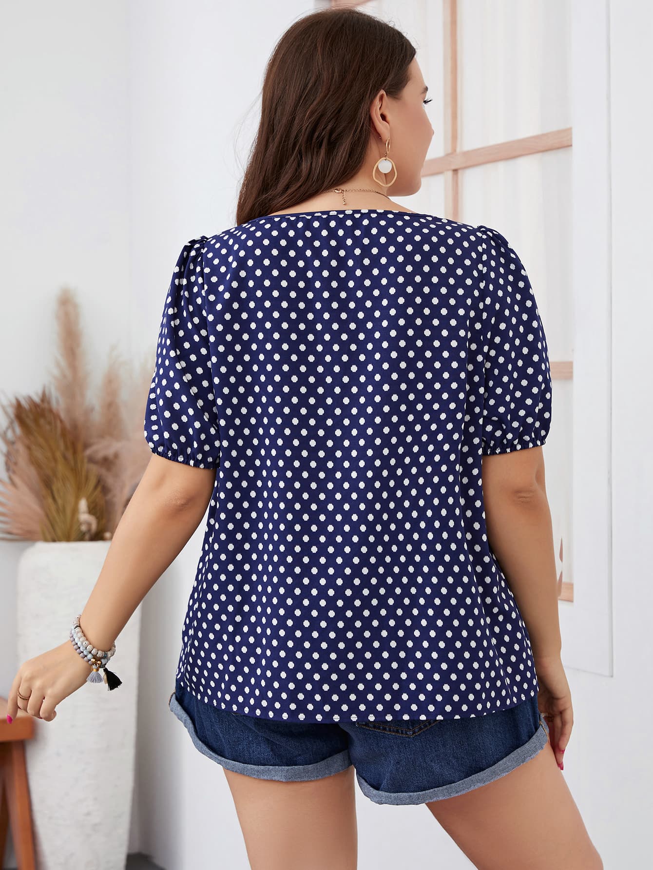 Model in a navy blue polka dot blouse, demonstrating its flattering fit and timeless pattern for everyday wea