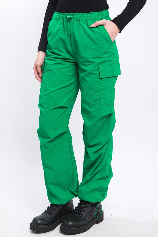 Close-up of green cargo pants showing functional side pockets and ankle fastenings.
