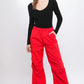 Red cargo pants featuring adjustable ankle fastenings and relaxed silhouette.
