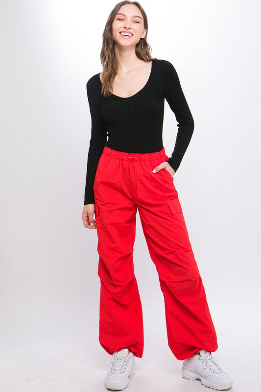 Red cargo pants featuring adjustable ankle fastenings and relaxed silhouette.
