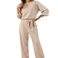 Front view of an apricot boat neck wide-leg jumpsuit featuring a waist tie.
