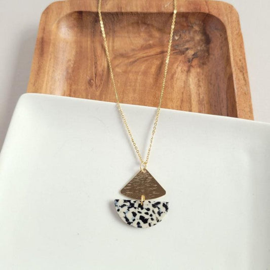 Gold triangle and black-and-white speckled half-moon pendant necklace.