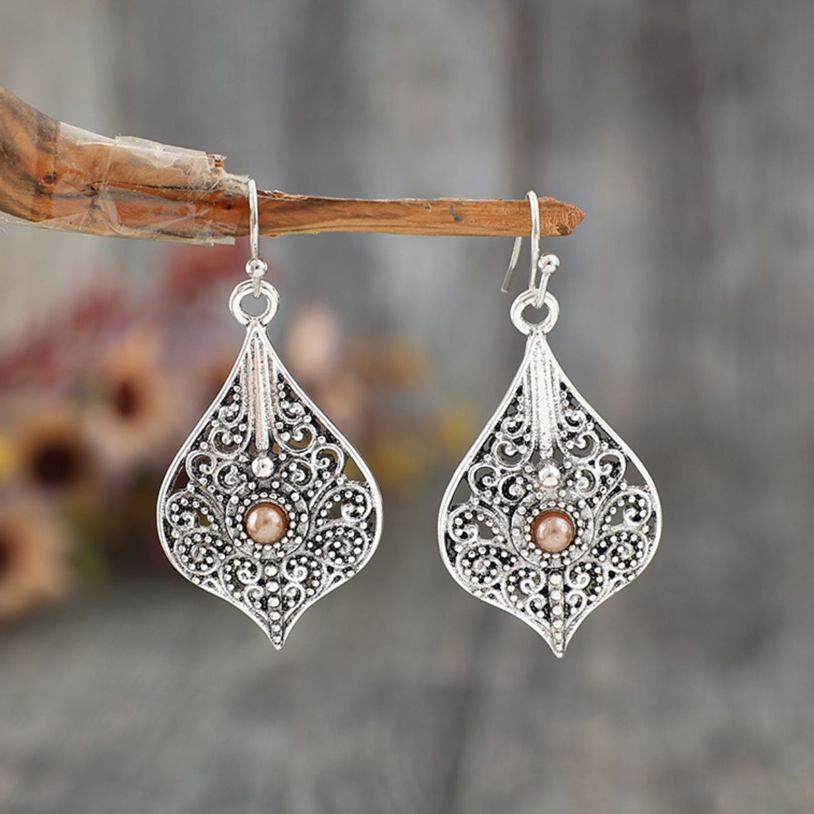 Vintage-style teardrop earrings with intricate silver filigree and a central bead