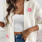 White cardigan featuring vibrant, knitted flower details.