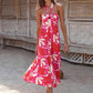 Woman wearing a floral maxi dress with a halter neck, standing on a beach.