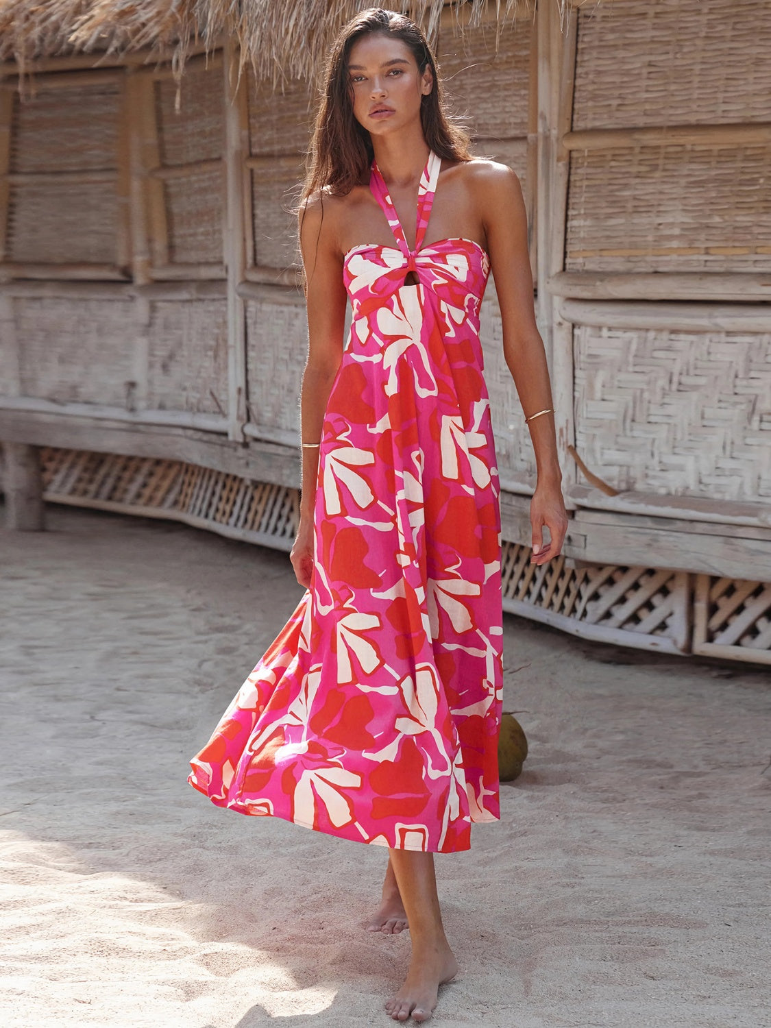 Woman wearing a floral maxi dress with a halter neck, standing on a beach.