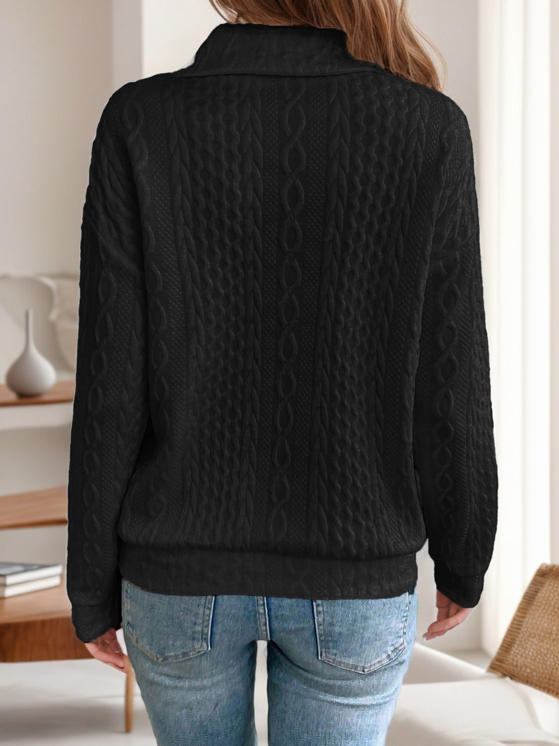 Back view of the black quarter-zip knit sweater, featuring its classic cable knit pattern and relaxed fit.

