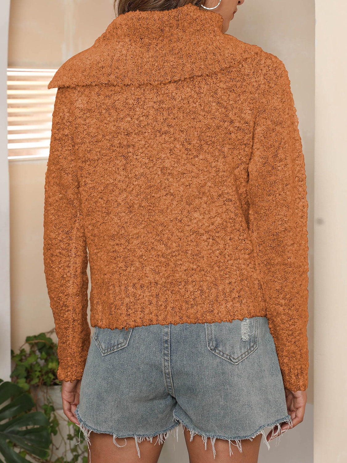 Back view of the orange button knit sweater, showcasing its comfortable fit and textured design.

