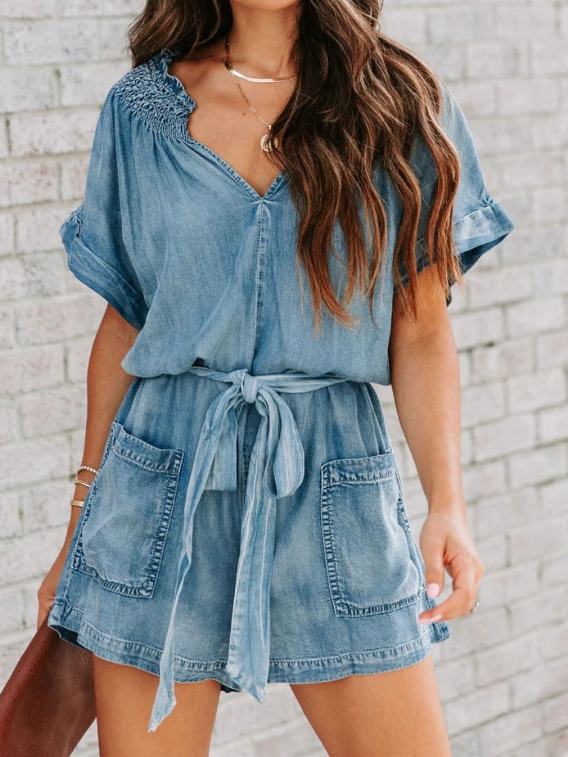 Chic denim romper with notched neckline and adjustable tie waist for a perfect fit. Versatile, comfortable, and perfect for summer days.