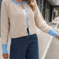 Cozy beige cardigan featuring blue contrast trim, made from soft fabric for comfortable wear.