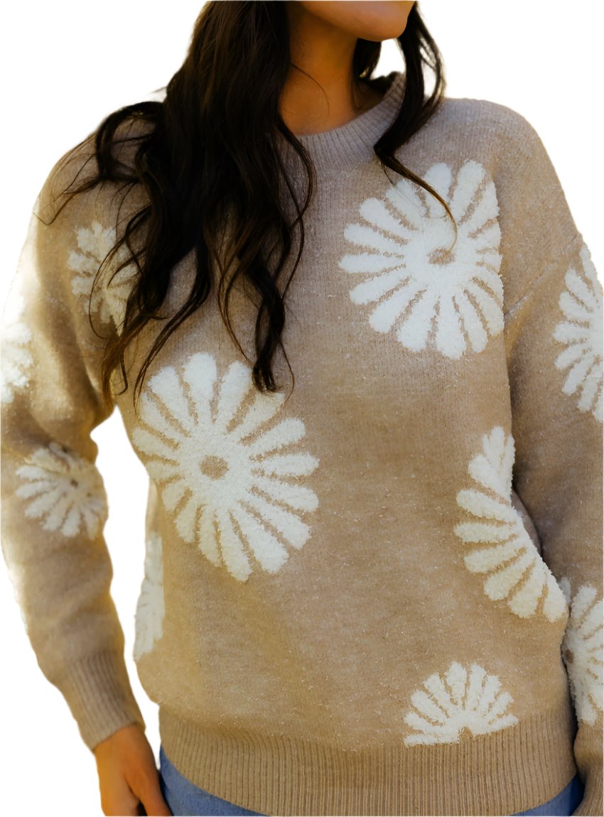 Woman wearing a beige daisy print knit sweater paired with jeans.
