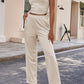 Beige women's pant suit featuring a long jacket and flowy wide-leg pants
