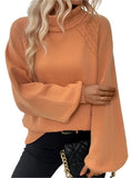 Woman wearing an orange bell sleeve turtleneck sweater styled with black pants