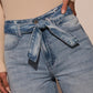 Closeup of detachable denim belt on light wash wide-leg jeans for a polished look.
