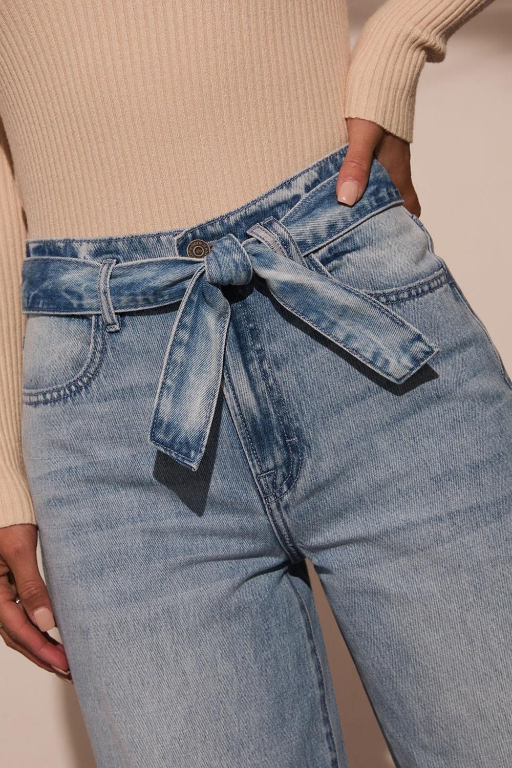 Closeup of detachable denim belt on light wash wide-leg jeans for a polished look.
