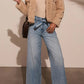 Styled outfit featuring belted high-waist wide-leg jeans in light wash paired with boots.
