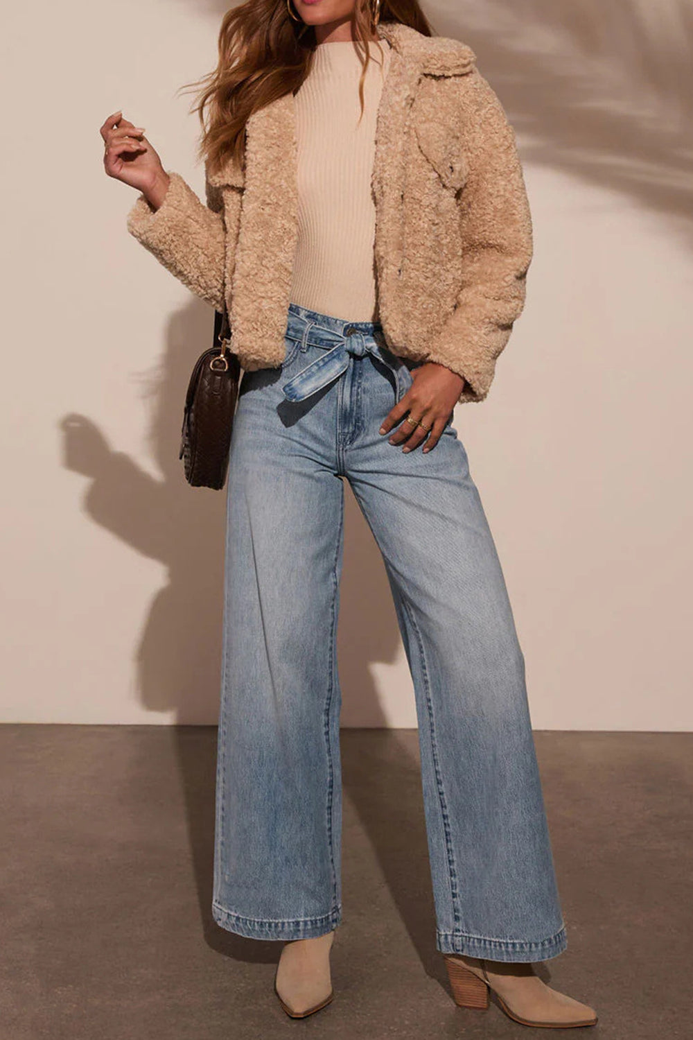 Styled outfit featuring belted high-waist wide-leg jeans in light wash paired with boots.
