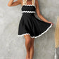 Flowy A-line black mini dress with white contrast trim.
