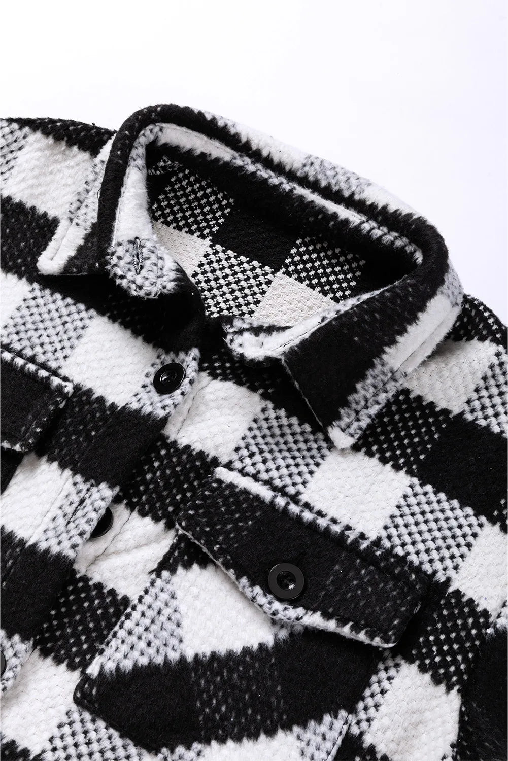 Front view of a black-and-white plaid shacket with pockets and snap buttons.
