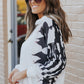 Side view of a black and white printed casual hoodie for women, styled with jeans.
