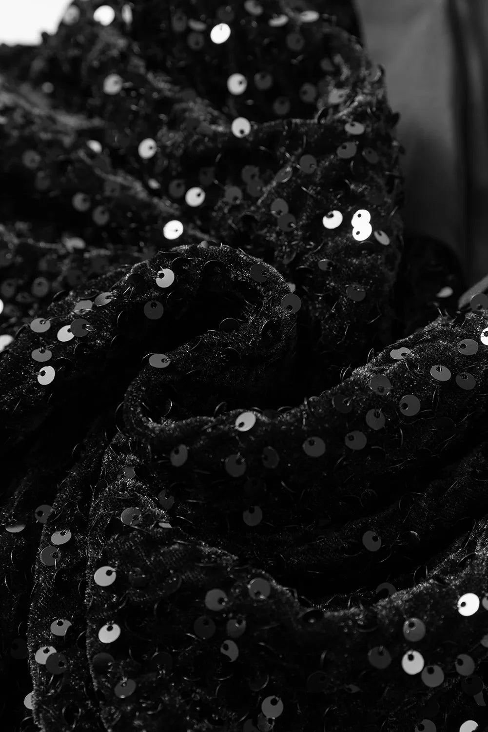 Close-up of black sequin fabric and bow detail on holiday dress.
