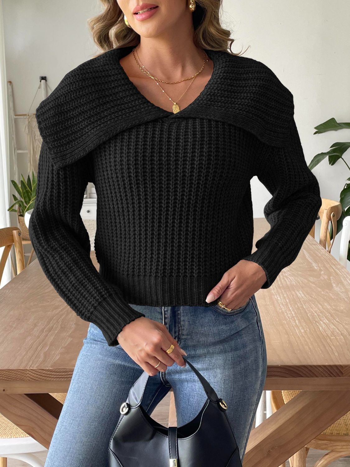 Warm black cable-knit sweater paired with light-wash denim.
