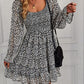 Black bohemian square-neck dress with floral print, long sleeves, and a chic ruffled hem.
