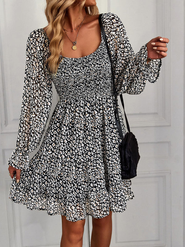 Black bohemian square-neck dress with floral print, long sleeves, and a chic ruffled hem.
