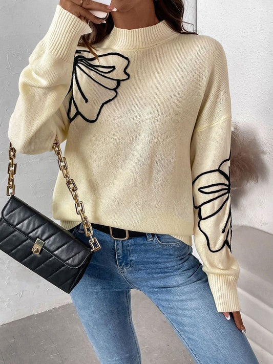 Casual butter yellow sweater with black floral accents, worn with jeans.
