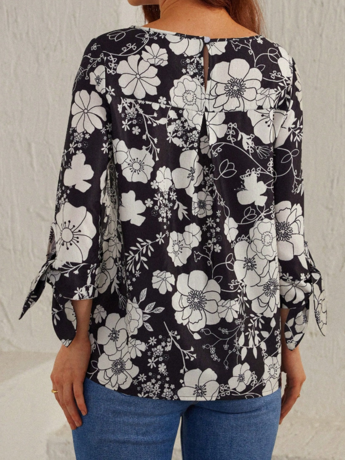 Women’s classic black and white floral blouse with tied sleeves for a feminine touch.
