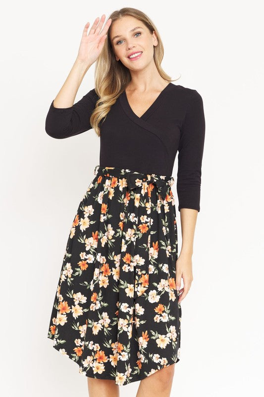 Women's black floral wrap dress with a flowing floral skirt.
