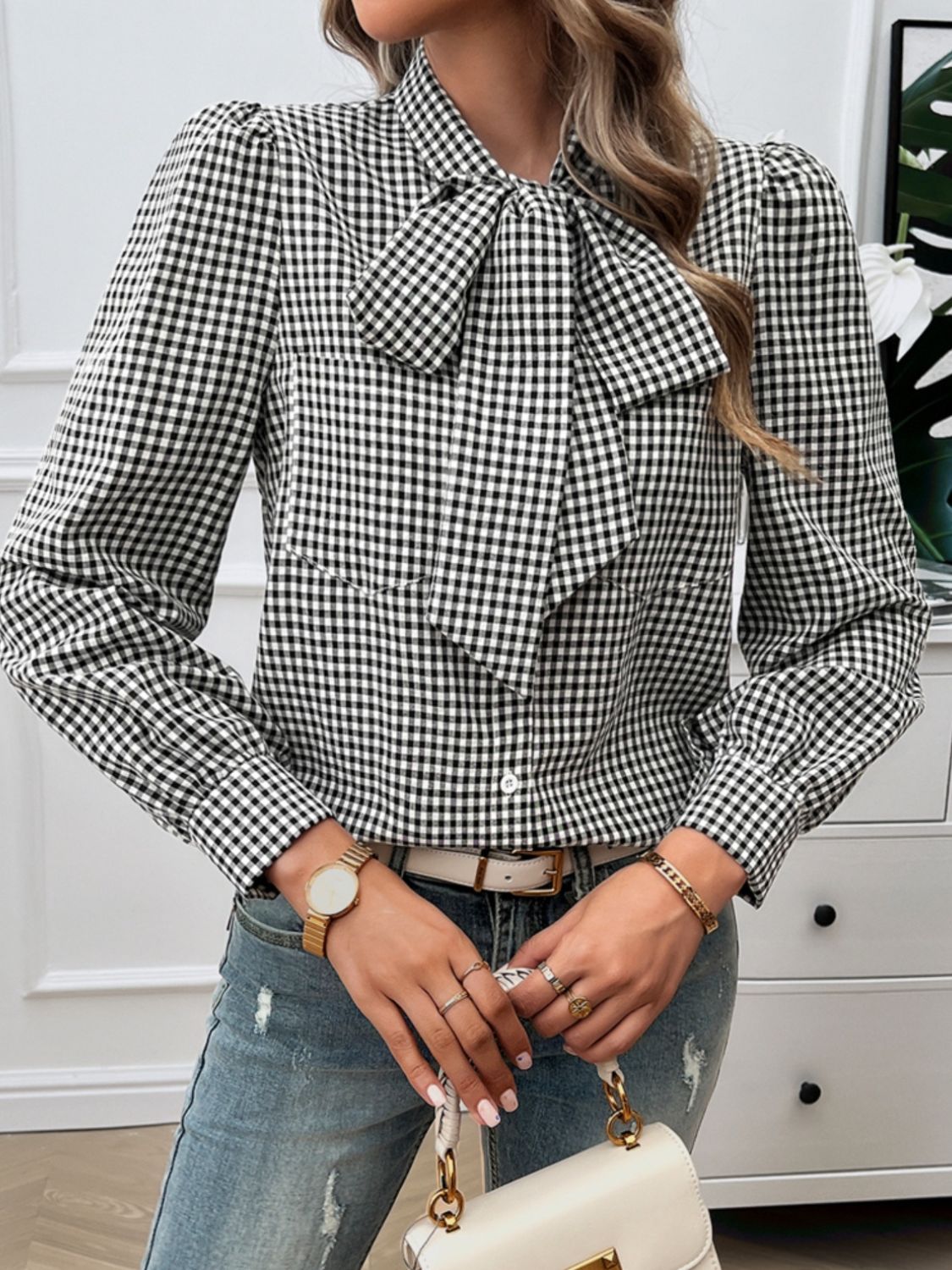 Black gingham blouse featuring a bow tie neck and puff sleeves, styled for work.
