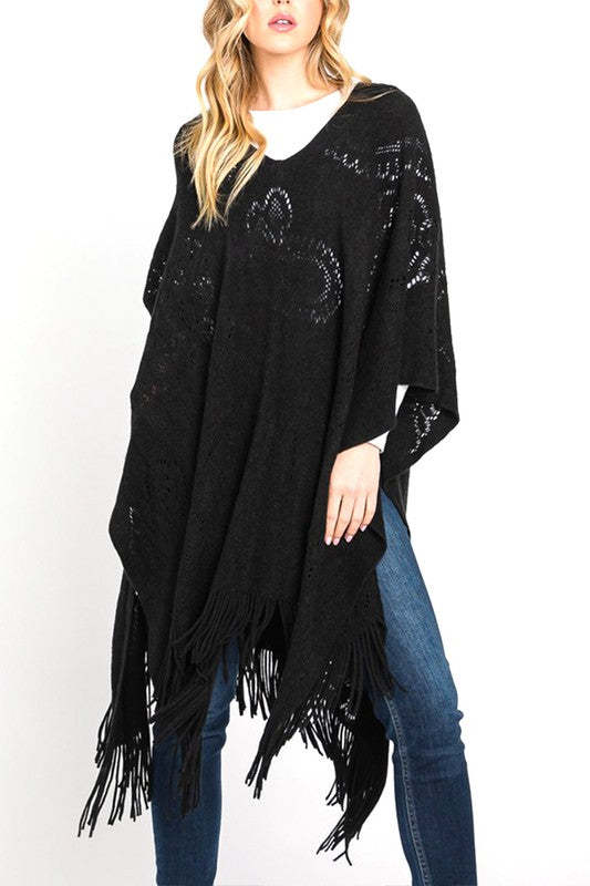 Black paisley perforated knit poncho with fringe hem, front view.
