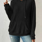 Woman wearing black ribbed drawstring hoodie with front pocket.
