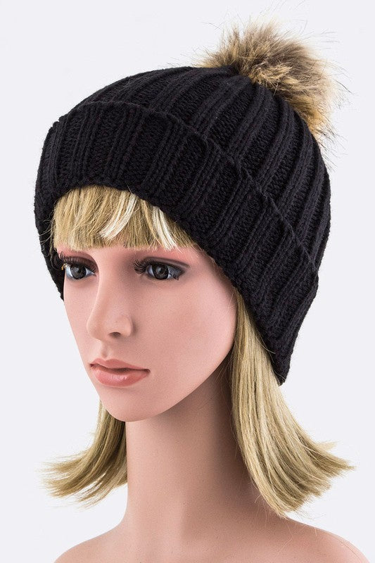 Black ribbed knit hat with a stylish faux fur pom for a chic look.
