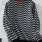 A stylish black striped knit sweater with wavy pattern, paired with casual bottoms.

