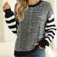 Front view of a black striped round neck sweater with a relaxed, dropped shoulder fit.
