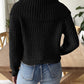 Black cable-knit sweater with wide collar, styled with denim jeans.
