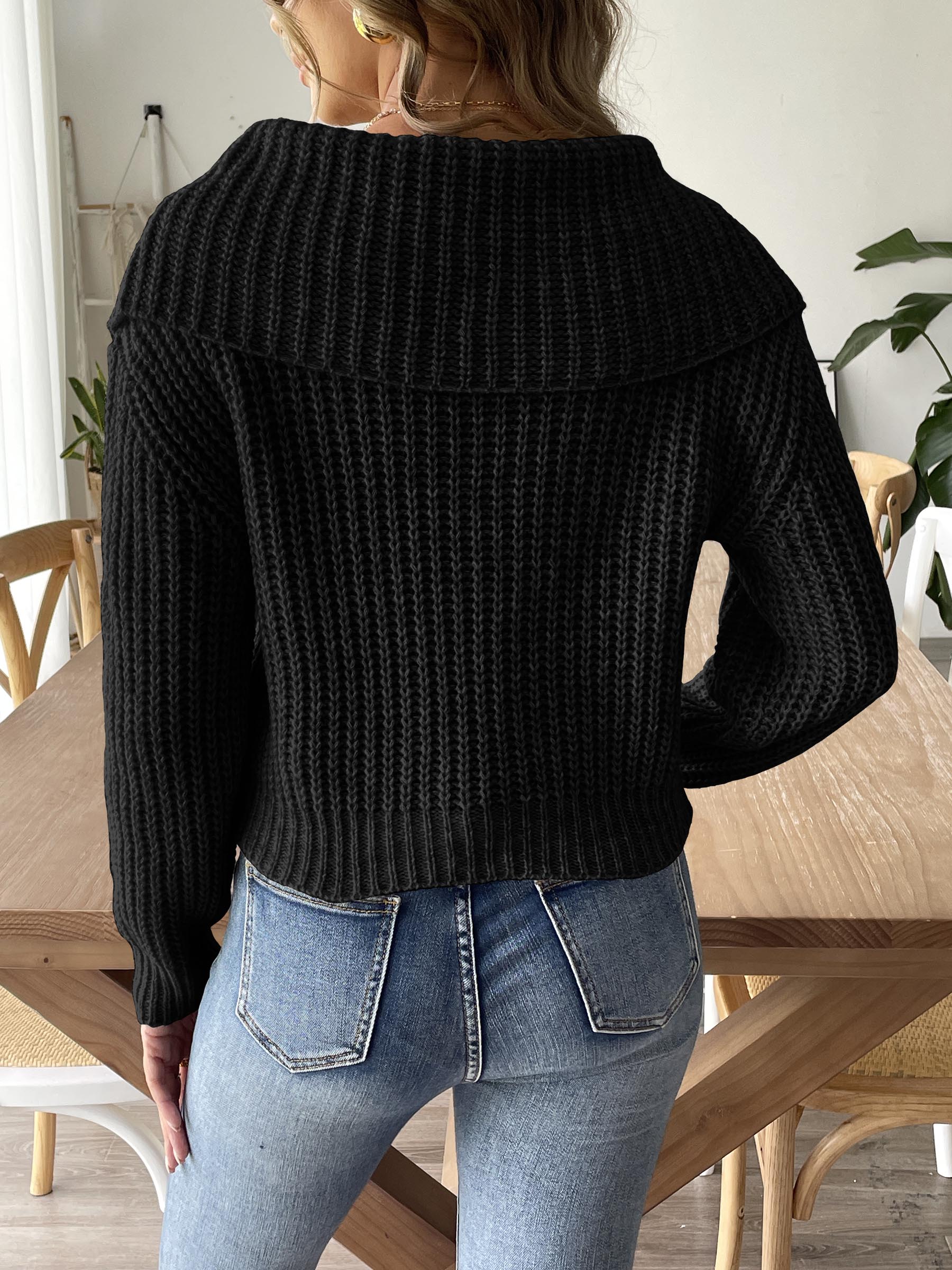 Black cable-knit sweater with wide collar, styled with denim jeans.
