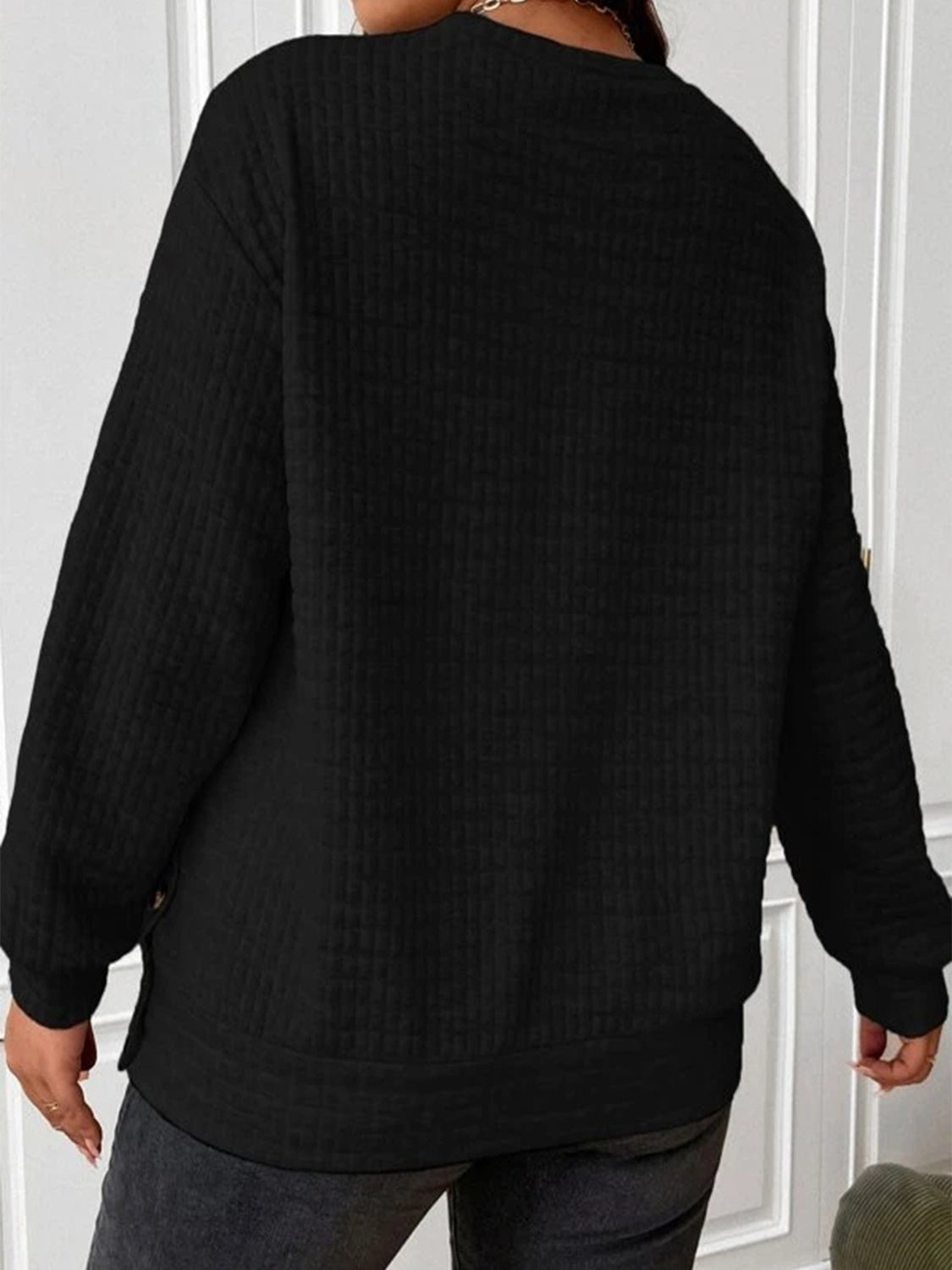 Black waffle-knit sweatshirt with a relaxed fit and side buttons for women.
