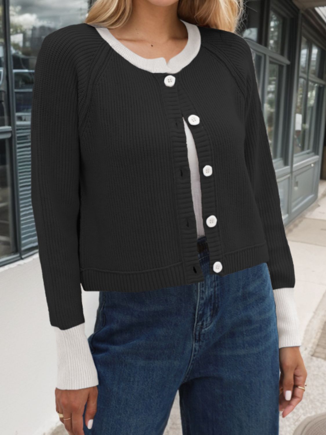 Black cardigan with white trim, buttoned down the front, perfect for stylish layering over casual outfits.