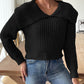 Woman wearing a black cable-knit wide collar sweater with jeans.
