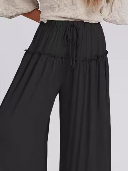 Detail of frill hem on black wide-leg pants, adding boho style to the look.
