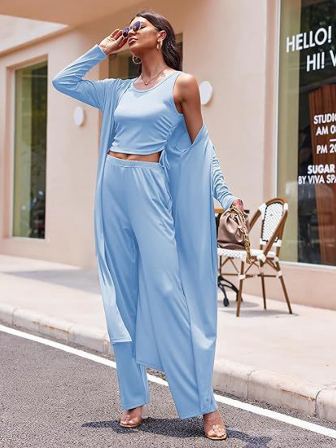 Woman wearing a blue 3-piece women's pant suit with wide-leg pants and a long duster jacket
