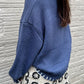 Blue knit sweater with an oversized bow detail, perfect for layering during cold winter months.

