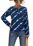 Woman wearing a blue tie-dye henley top with wooden-style buttons and long sleeves, paired with jeans.
