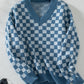 Trendy blue sweater featuring a checkerboard pattern and V-neckline.
