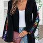 Black boho cardigan with a relaxed fit and vibrant sleeve embroidery.
