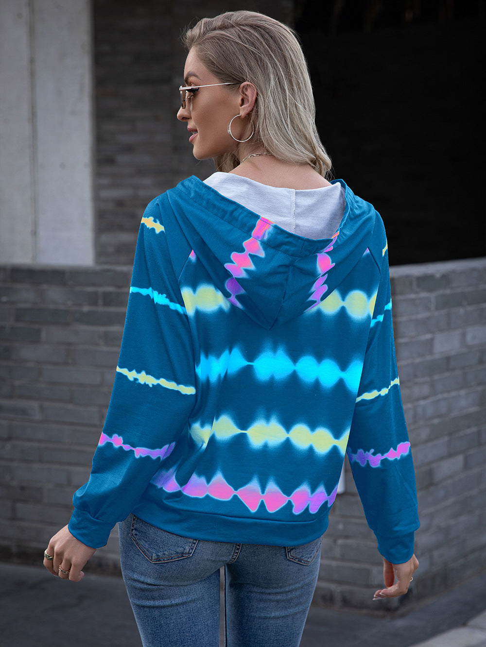 Blue tie-dye hoodie with a relaxed fit and drawstring hood, styled for a casual yet vibrant outfit.